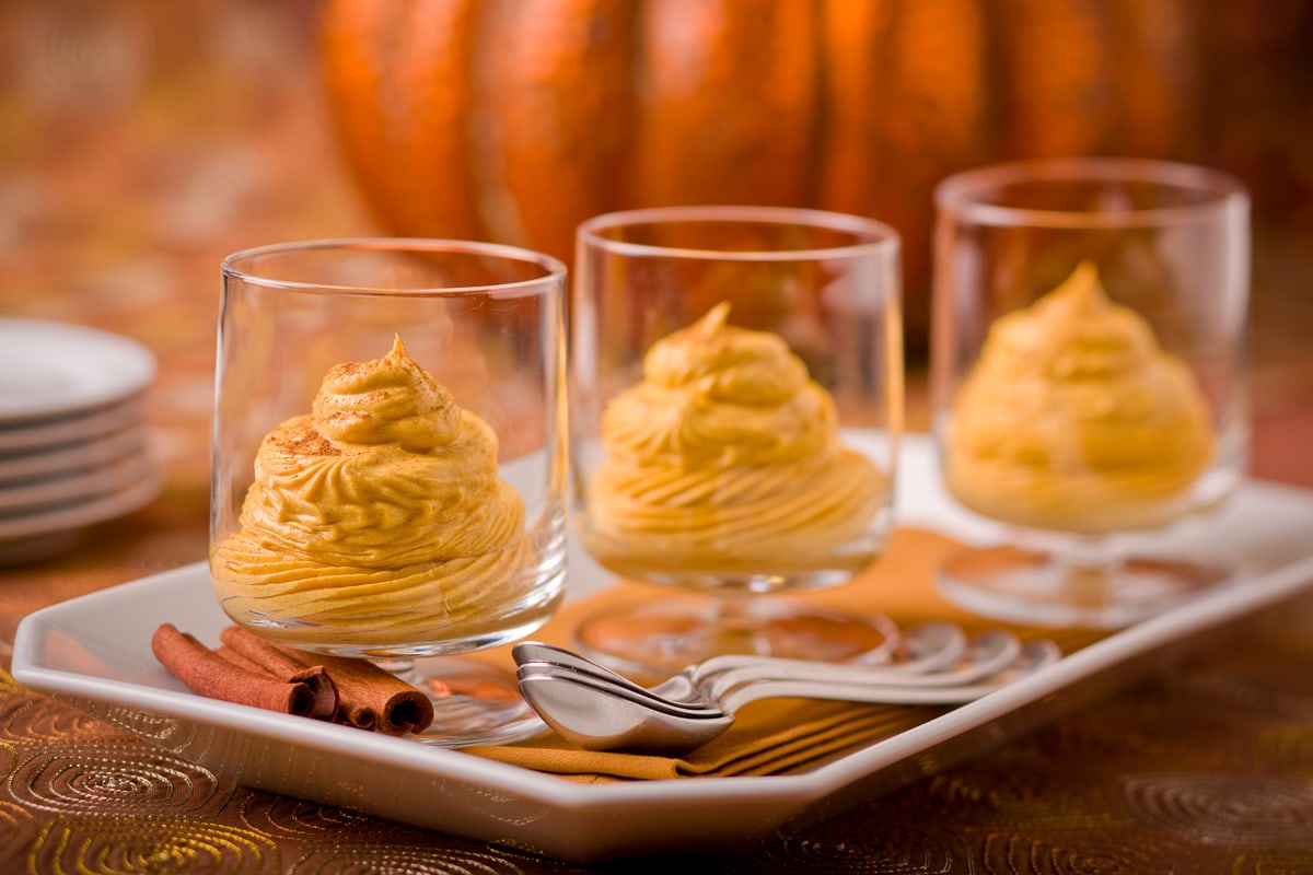 Beautiful orangey colored creamy pumpkin mousse piped into glasses for serving.