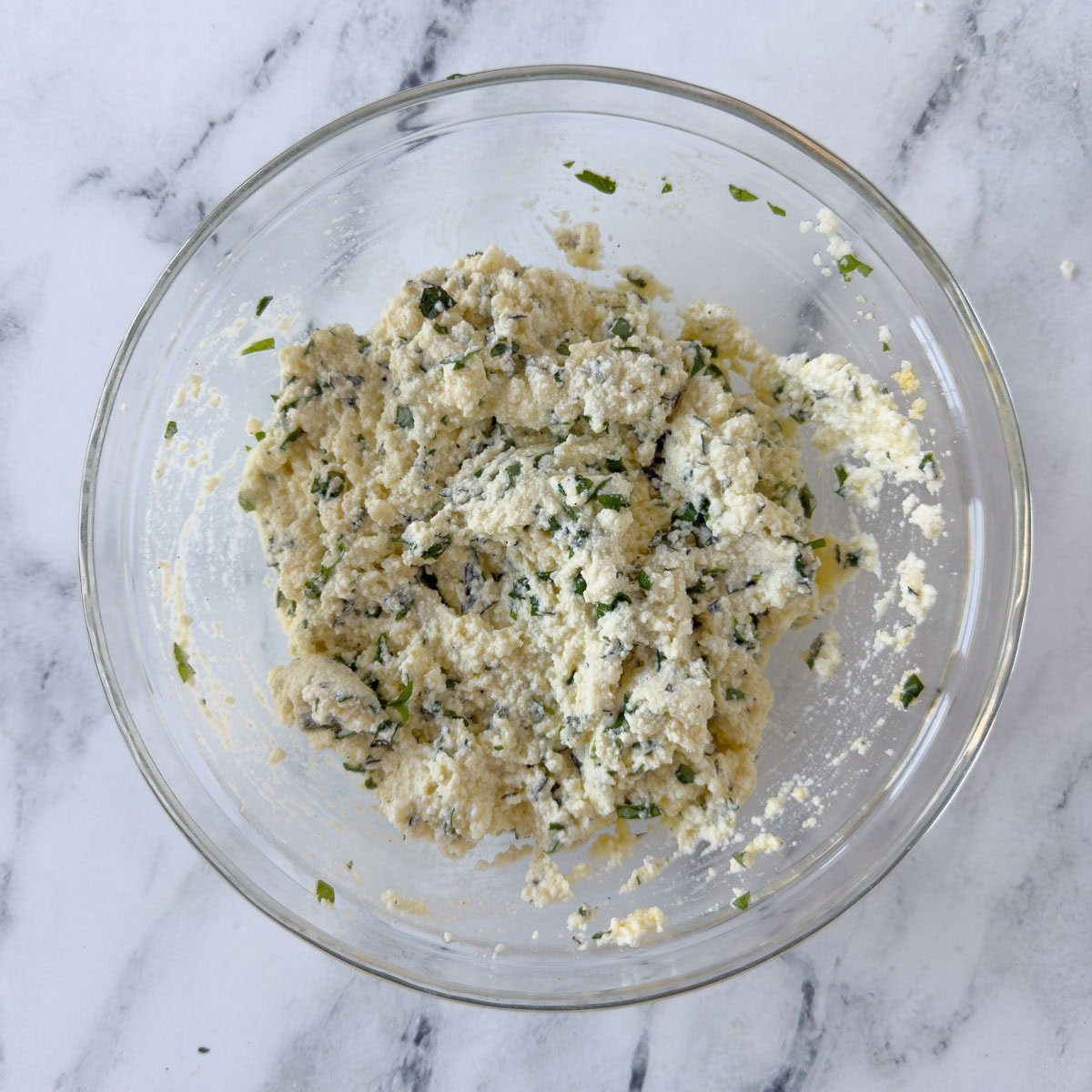 Ricotta cheese filling for lasagna in a glass bowl.
