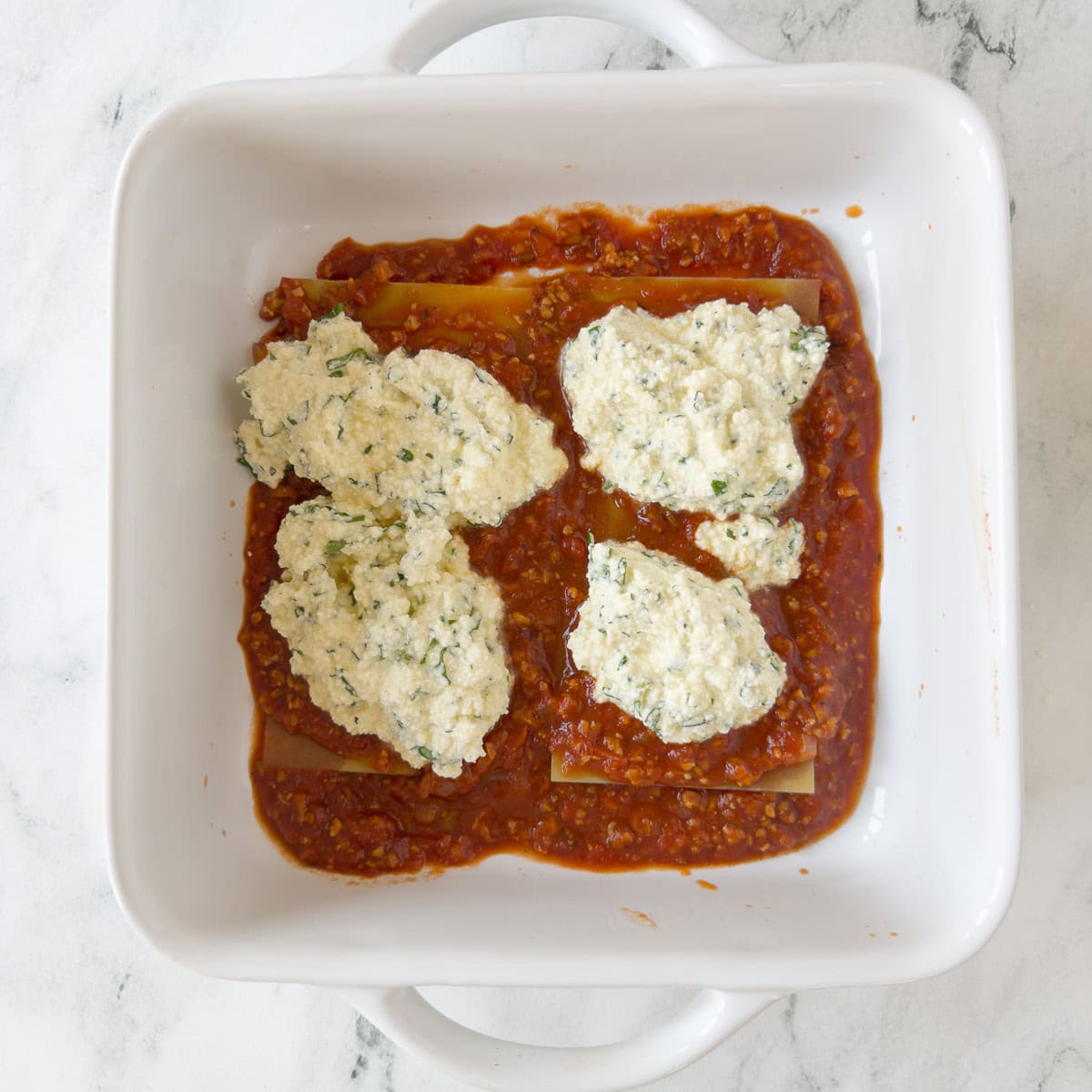 Gluten free lasagna layer with oven ready noodles, and sauce, with ricotta cheese topping.