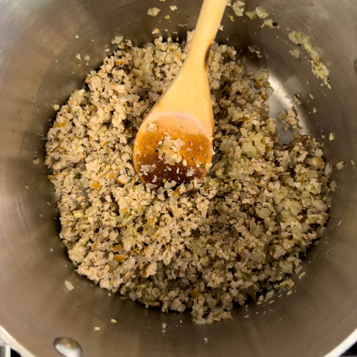 Cooking ground sausage and onions in a pot for lasagna sauce.