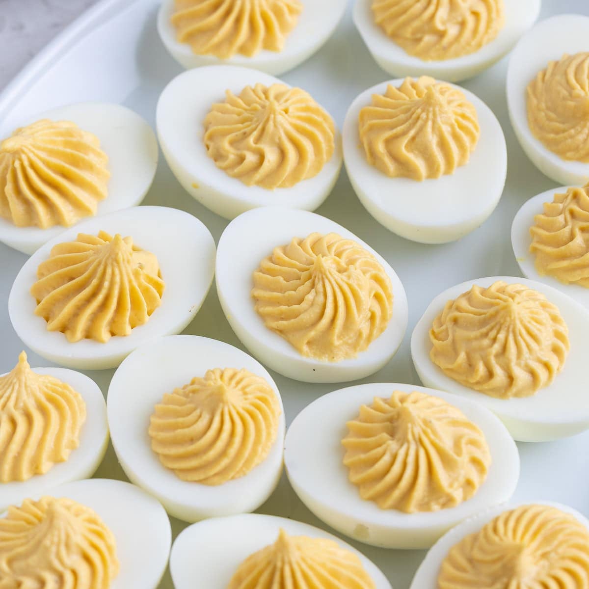 Hard boiled egg halved filled with deviled egg filling on a white plate.