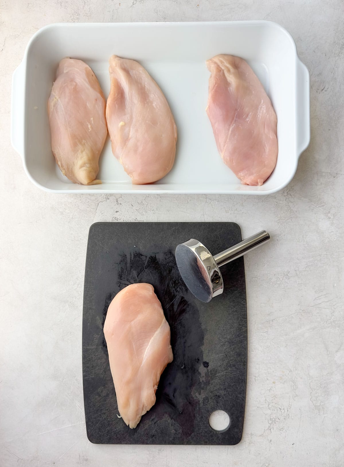Raw boneless skinless chicken breasts in a casserole dish.