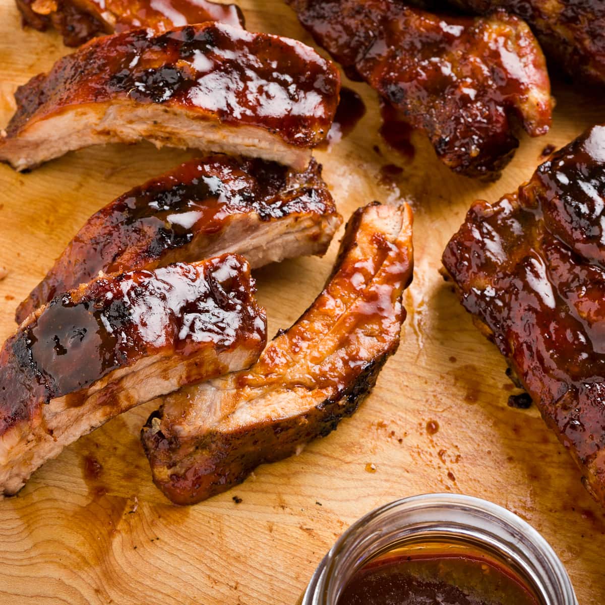 Oven baby back ribs glazed with rich brown hoisin sauce in a cutting board.