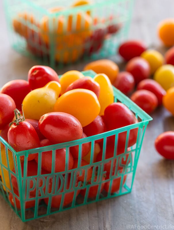 Red and yellow cherry tomatoes in a green basket.