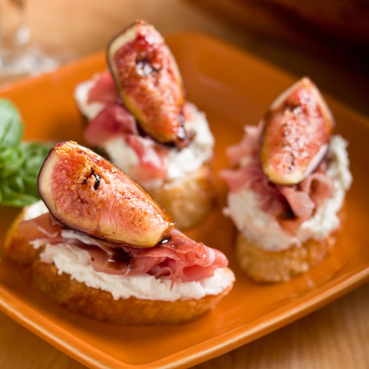Fig and goat cheese crostini with Prosciutto on a plate.