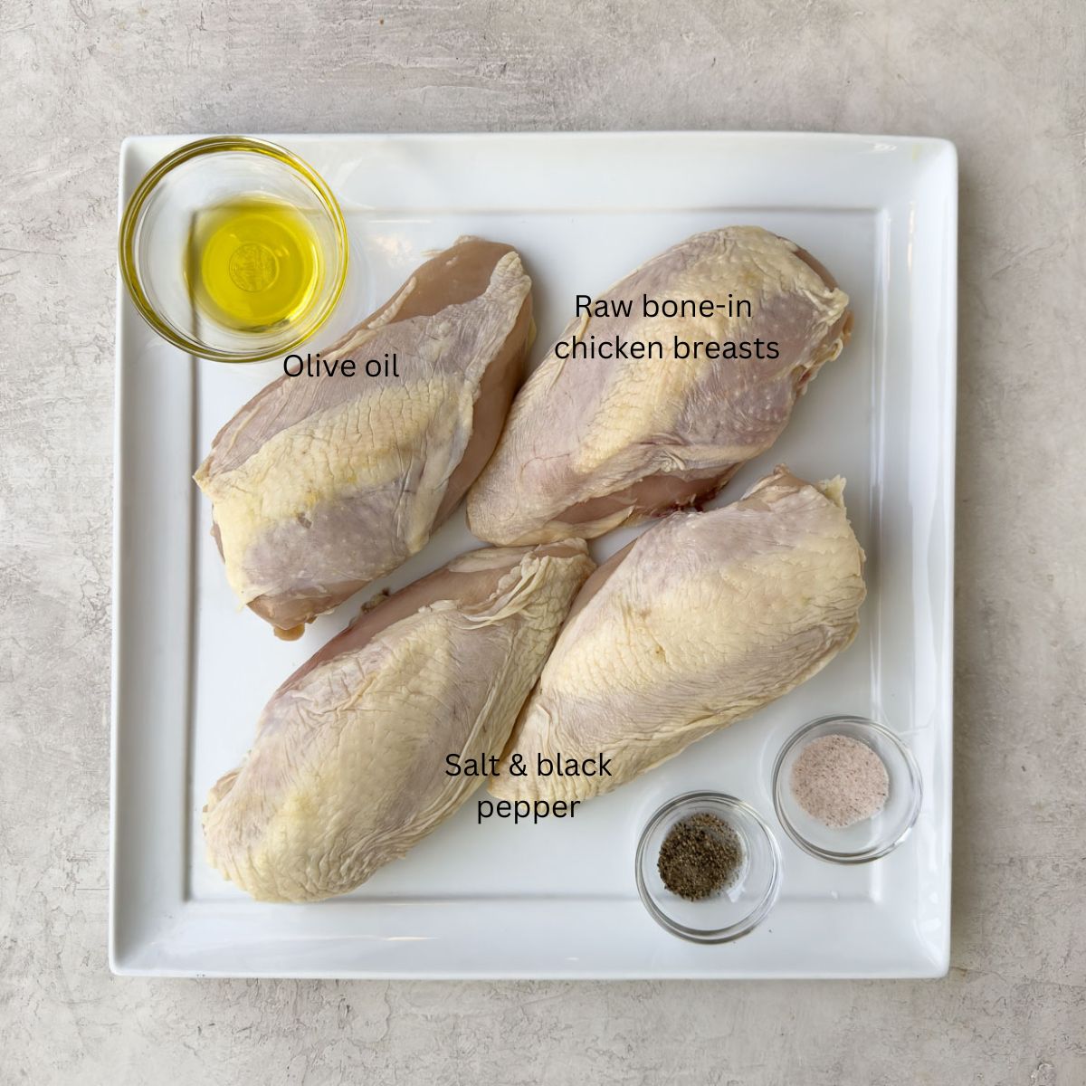 Raw bonin chicken breasts on a white platter.