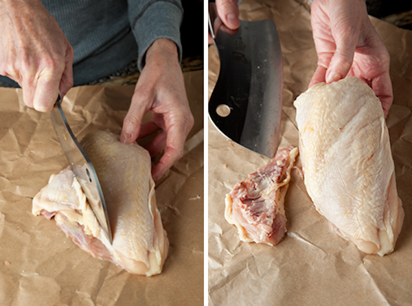Trimming chicken breasts on a cutting board.