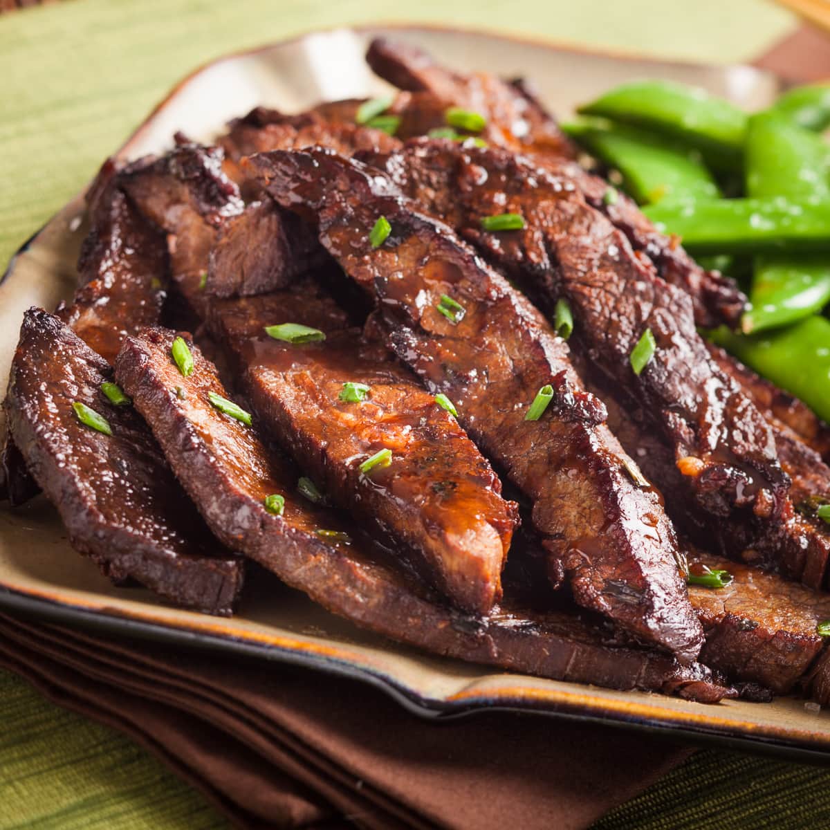 Asian ginger flank steak piled on a plate.