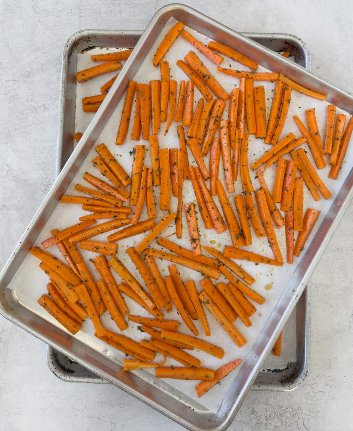 Two trays of cut carrots on baking trays with parchment.