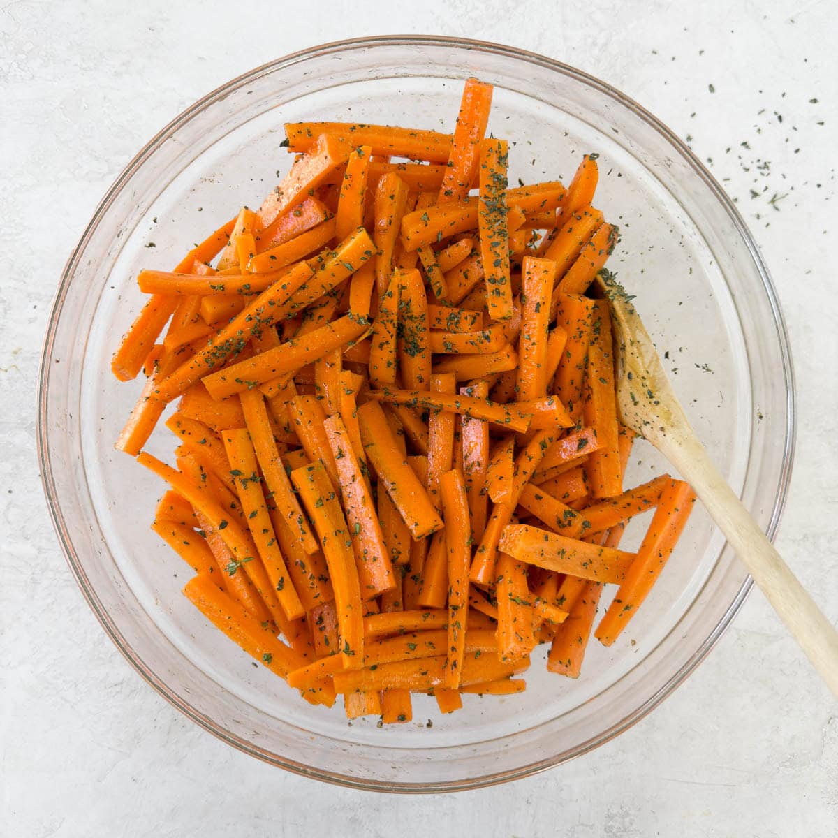 Julienned carrots in a bowl tossed with olive oil, salt, pepper, and fresh thyme leaves.