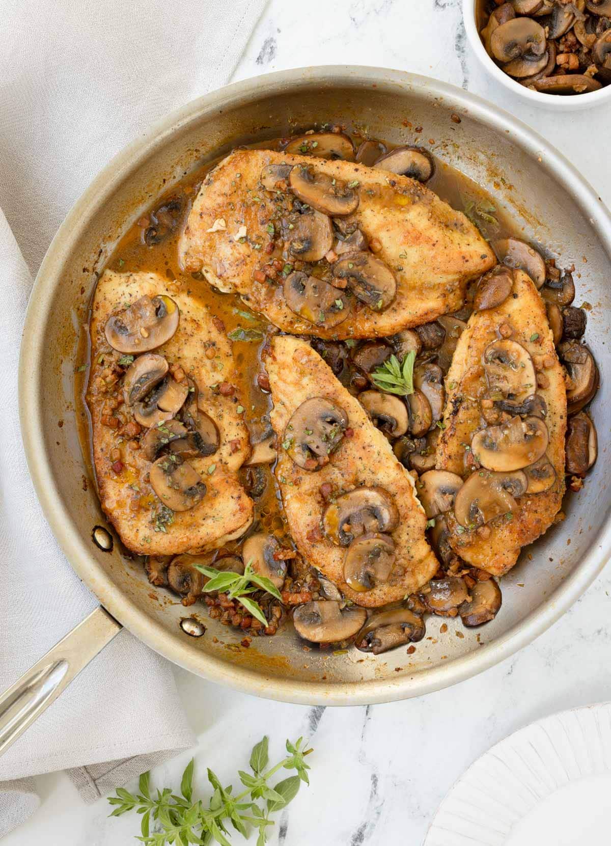 A saute pan of chicken marsala with a rich mushroom sauce and fresh oregano.