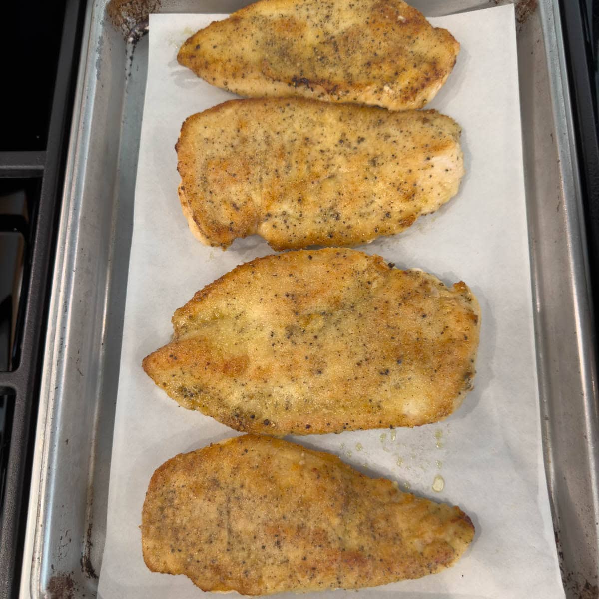Golden, crisp chicken cutlets on a sheet pan lined with parchment.