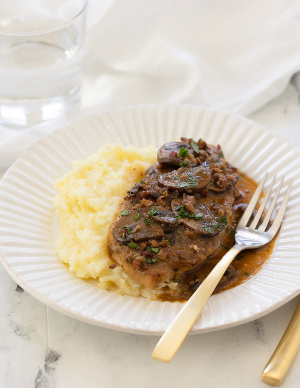 A plate of chicken marsala with creamy mashed potatoes and mushroom sauce.