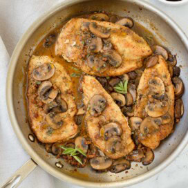 A saute pan of Chicken Marsala without cream, topped with mushroom sauce and herbs.