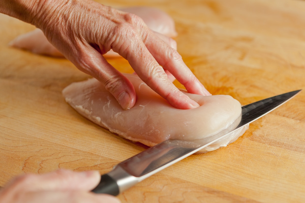 Slicing a chicken breast in half to make cutlets.