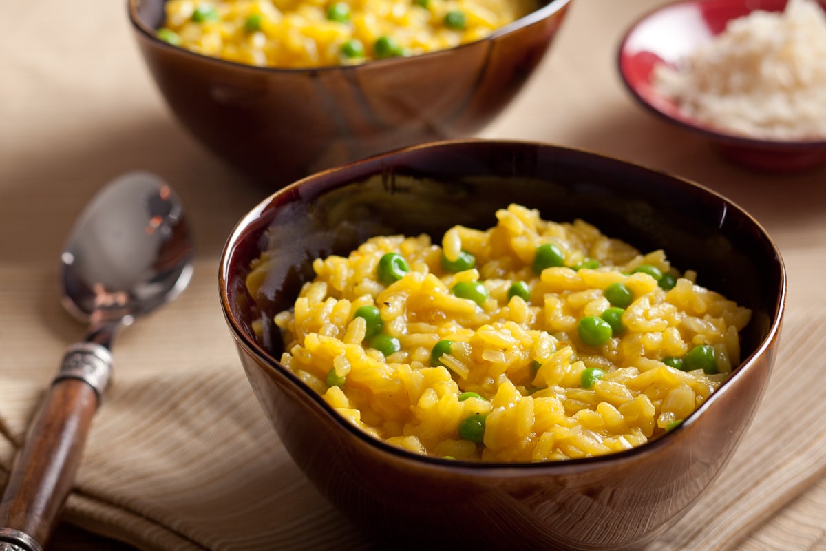 Golden risotto Milanese with saffron and peas in a bowl served as a side dish.