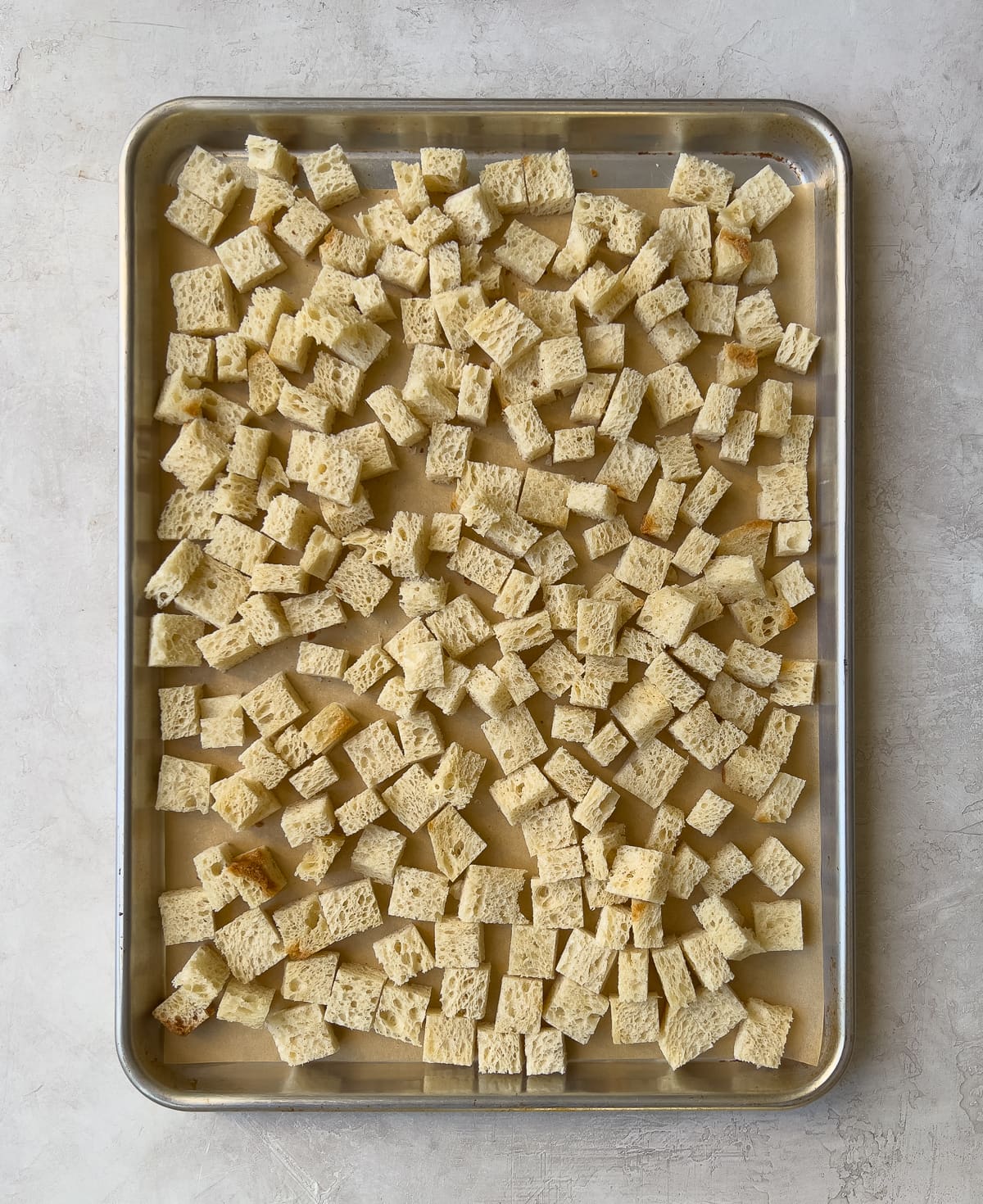 Bread cubes drying on baking sheet.