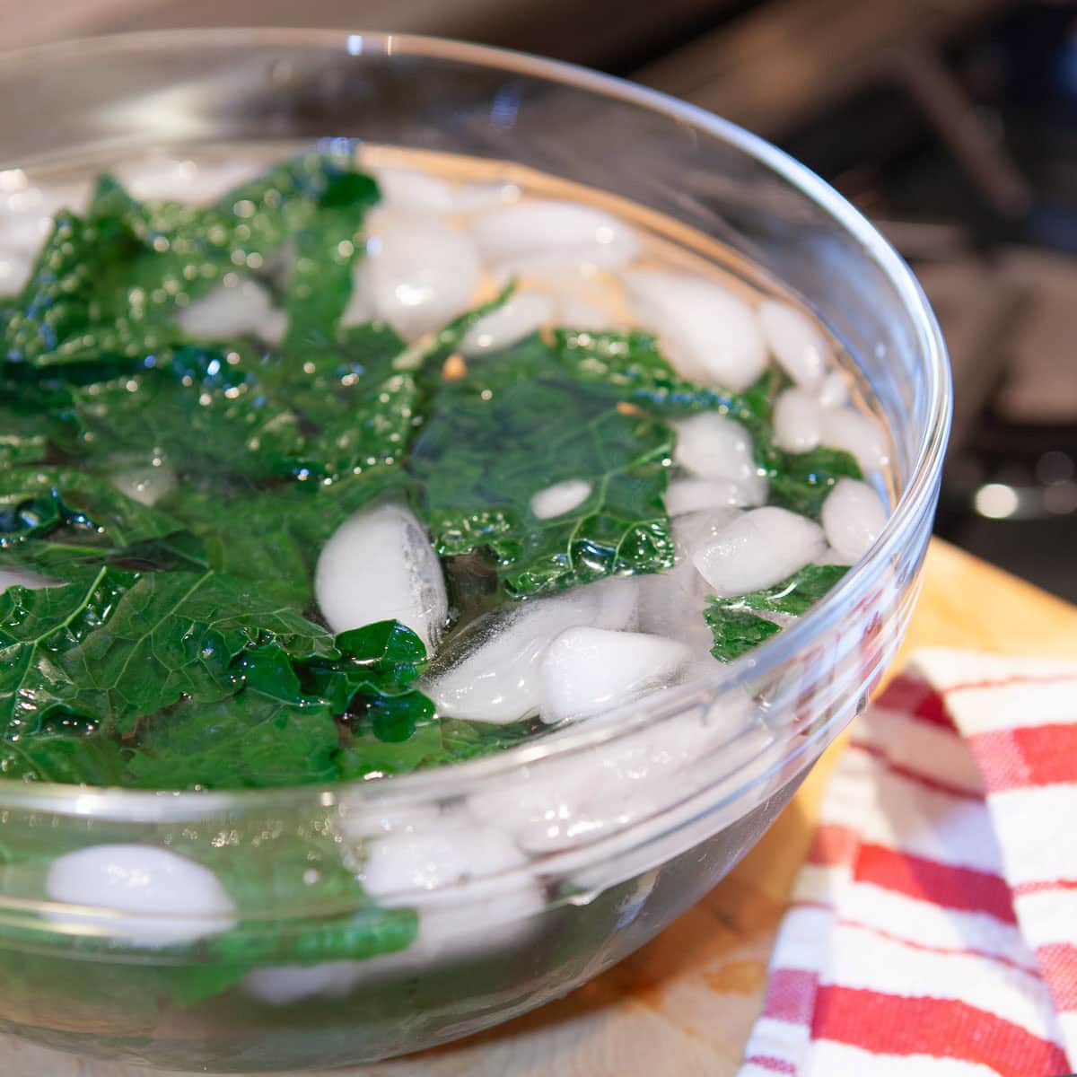 Shocking cooked kale in ice water to stop the cooking process and chill leaves.