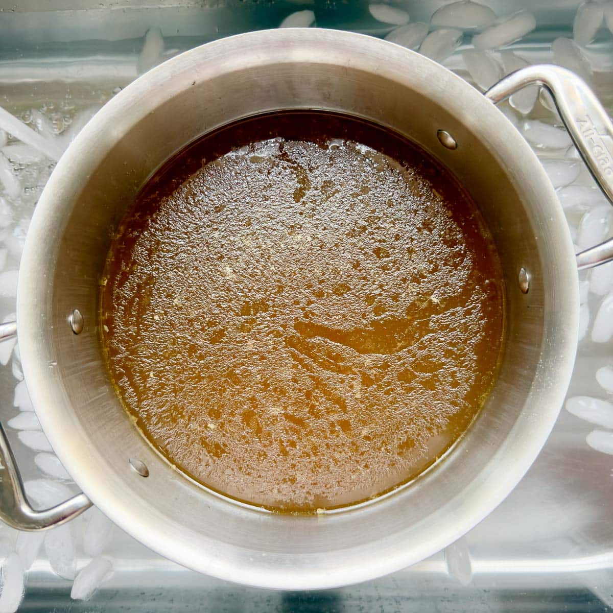 Chilling a pot of golden bone chicken bone broth in an ice bath in the sink.