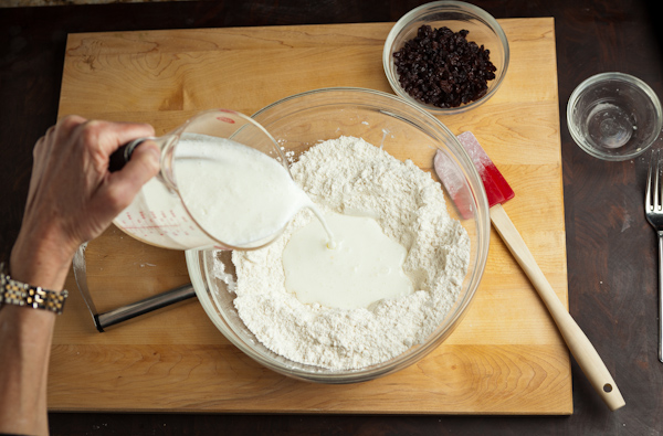Adding milk to the flour in a glass bowl.