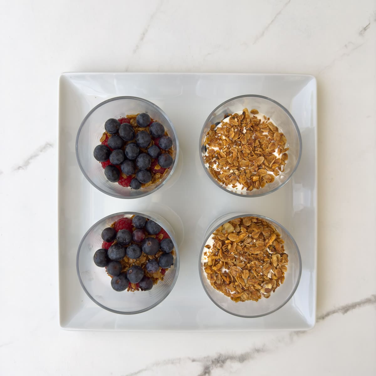 The next layer of ingredients in a yogurt parfait, berries and granola with yogurt. 