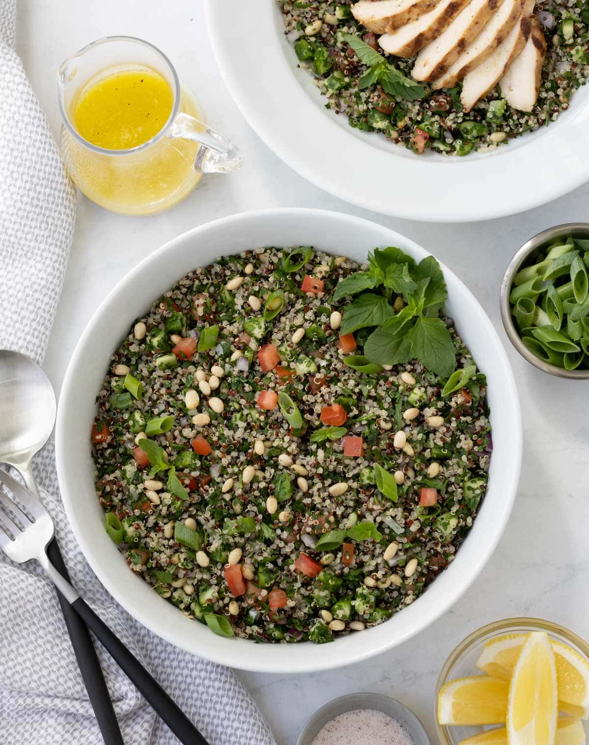 A bowl of tabouli with lots of green parsley, mint, tomatoes, quinoa, and pine nuts.