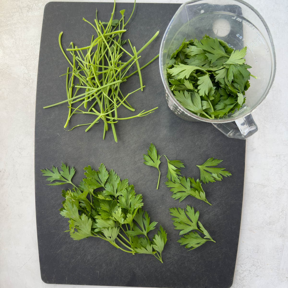 Separating the parsley leaves from the stems on a cutting board.