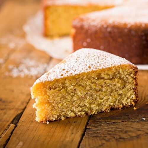 A slice of lemon almond cake with powdered sugar dusting.