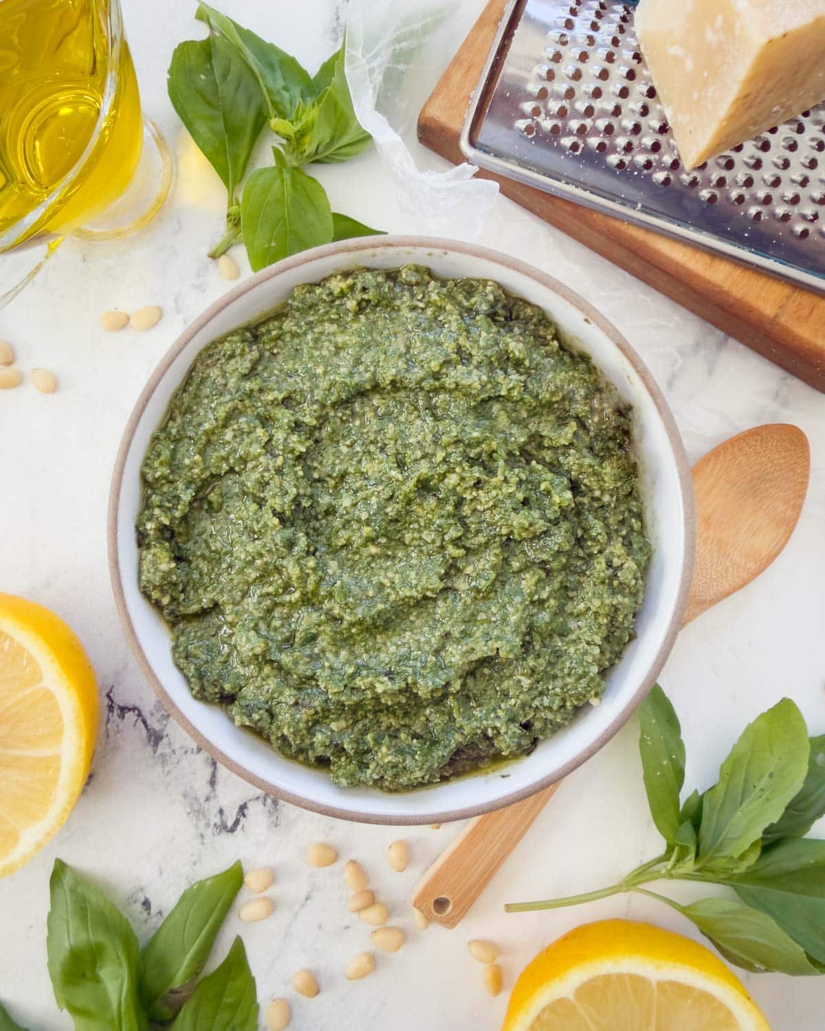 A bowl pf pesto alla Genovese, or basil pesto, with basil leaves, oil, lemons, and parmesan.