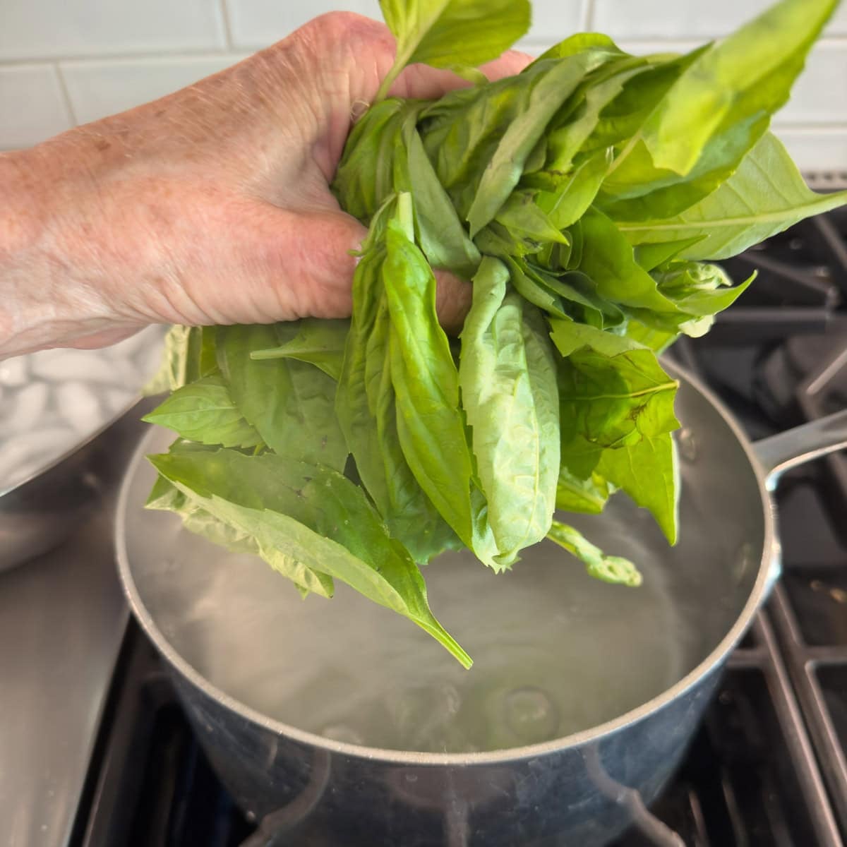 Blanching basil leaves in a pot of boiling salted water.