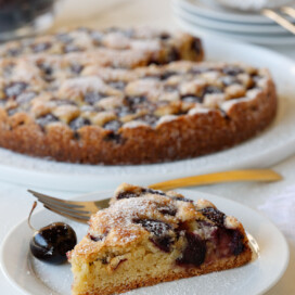 Baked cherry cake with a slice on a small plate.