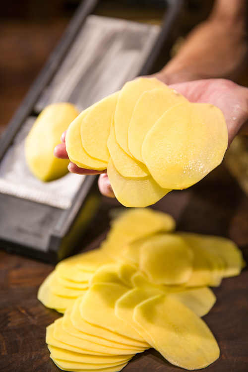 Thinly slicing potatoes with a mandolin.