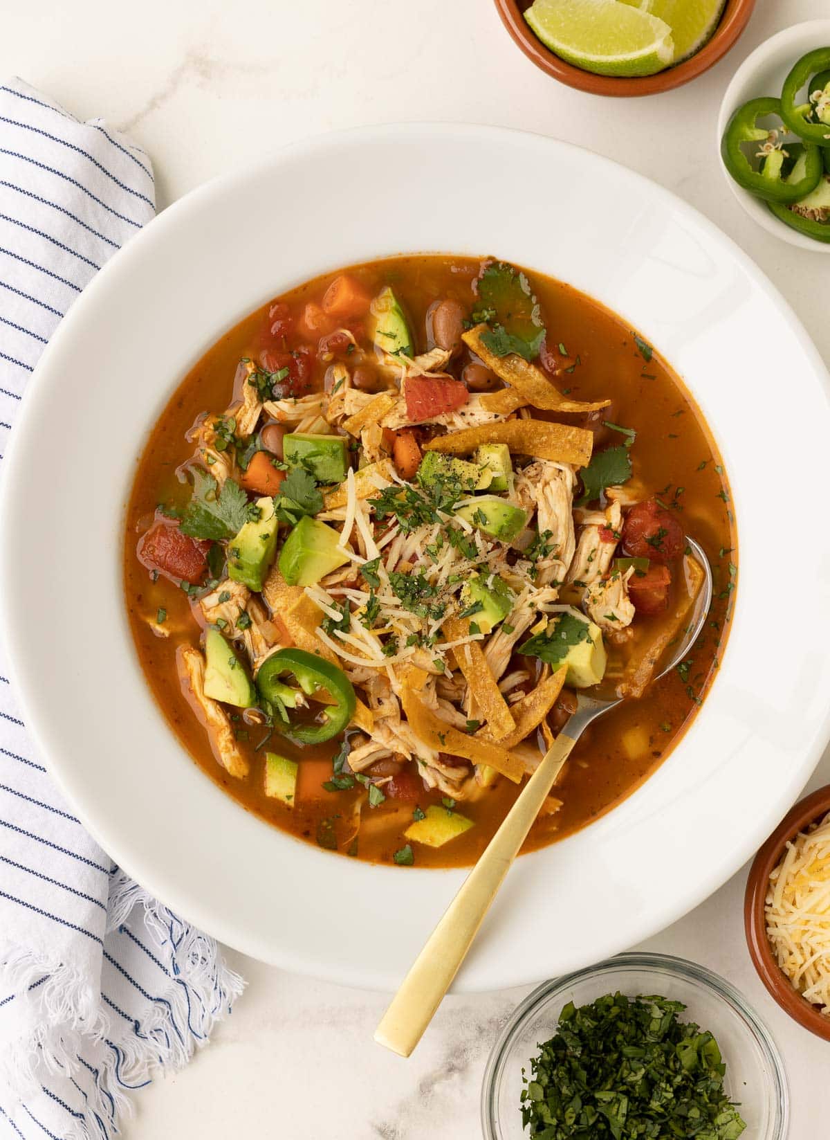 Mexican tortilla soup, ready to serve with garnishes in side bowls.