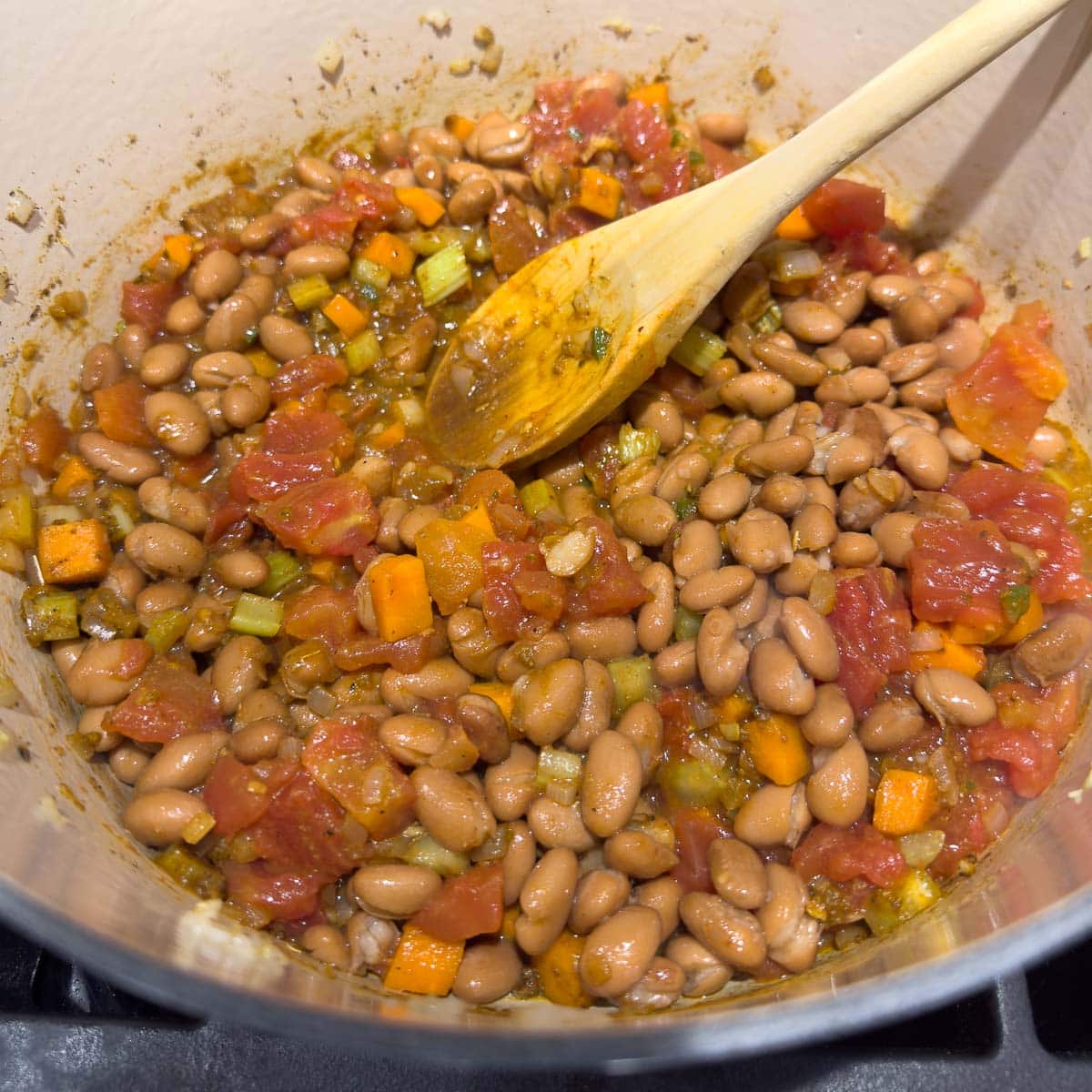 Now adding the beans and diced tomatoes to the vegetables, herbs and spices. 