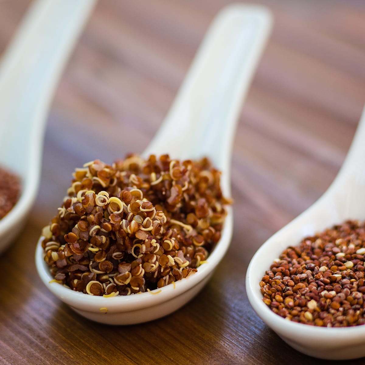 Raw and cooked quinoa on Chinese spoons. 
