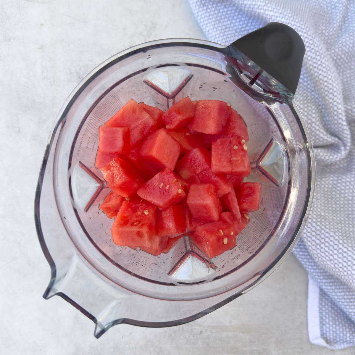Top down view of bright red watermelon cubes in a blender.