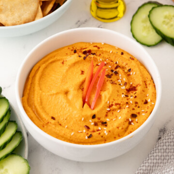 A white bowl of roasted red pepper hummus to serve as an appetizer.