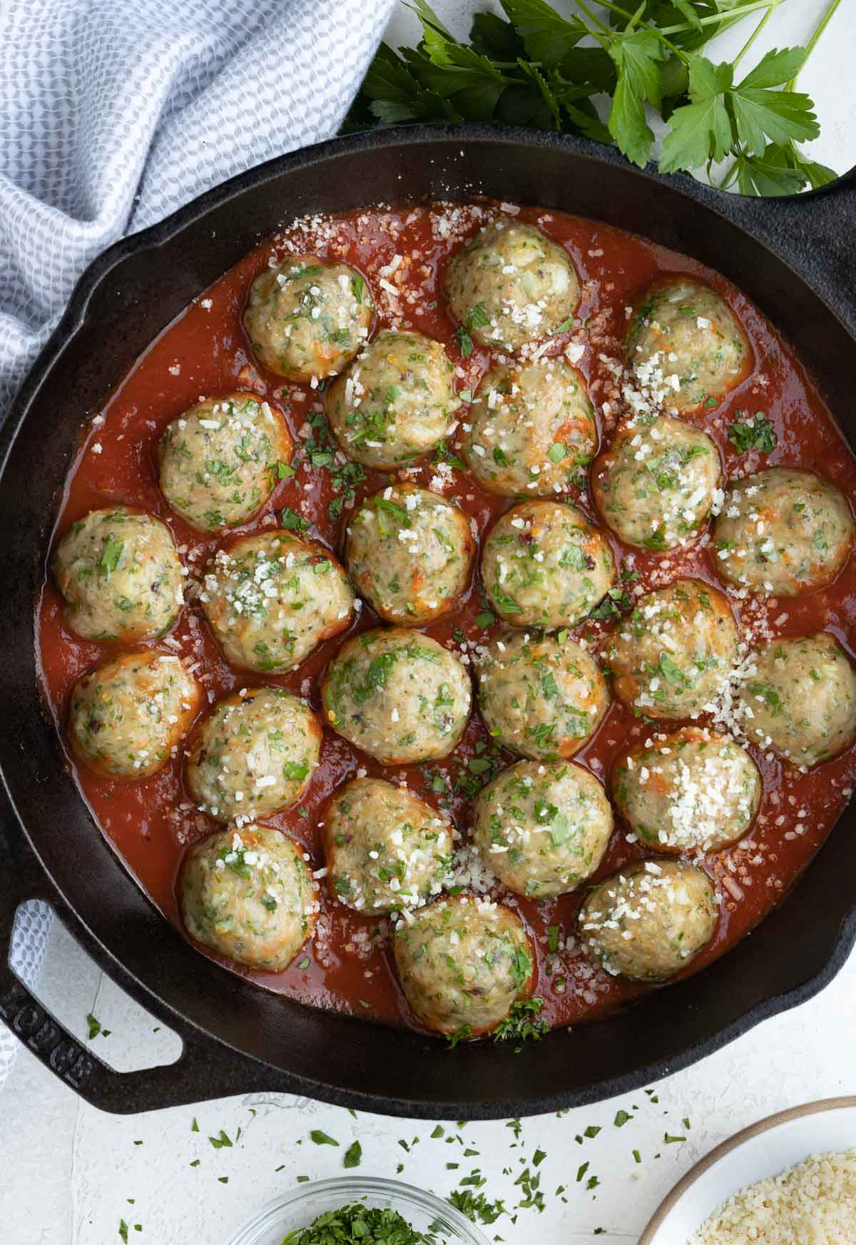 Baked turkey meatballs with red marinara sauce in a cast iron skillet.