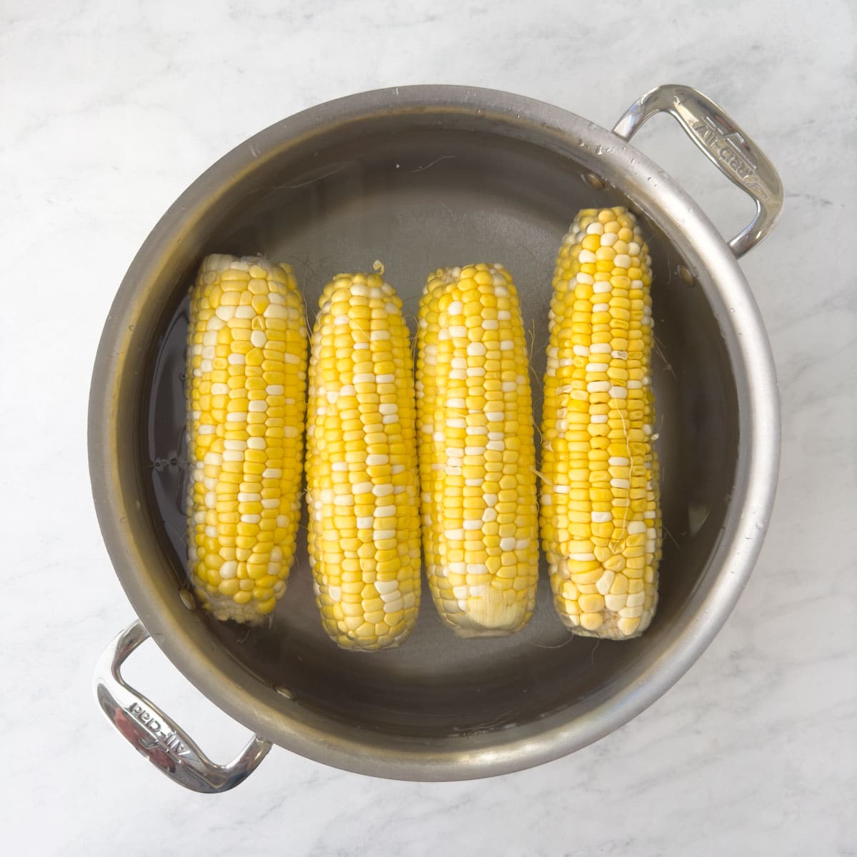 Cooking yellow corn on the cob in a pot of boiling water.