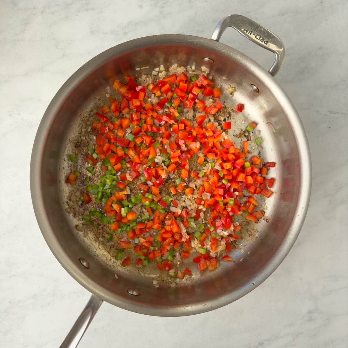 Sautéing red and green pepper in a saute pan.