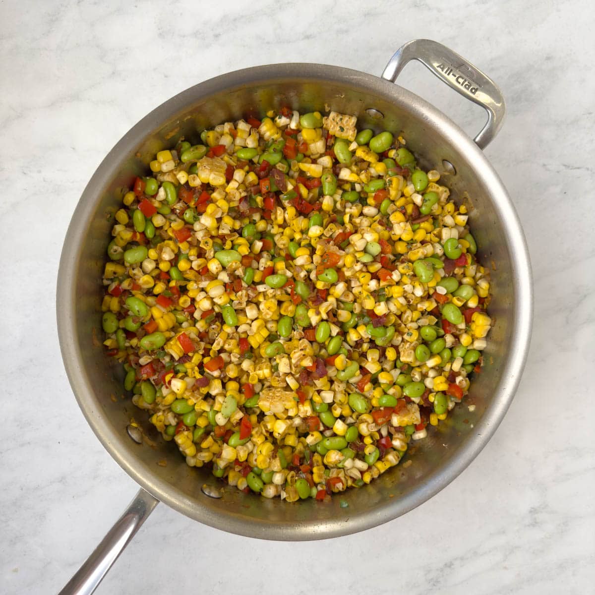 Colorful corn, red and green peppers and bacon in a saute pan.