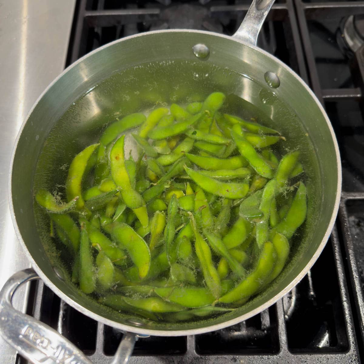 Cooking bright green edamame in boiling water.