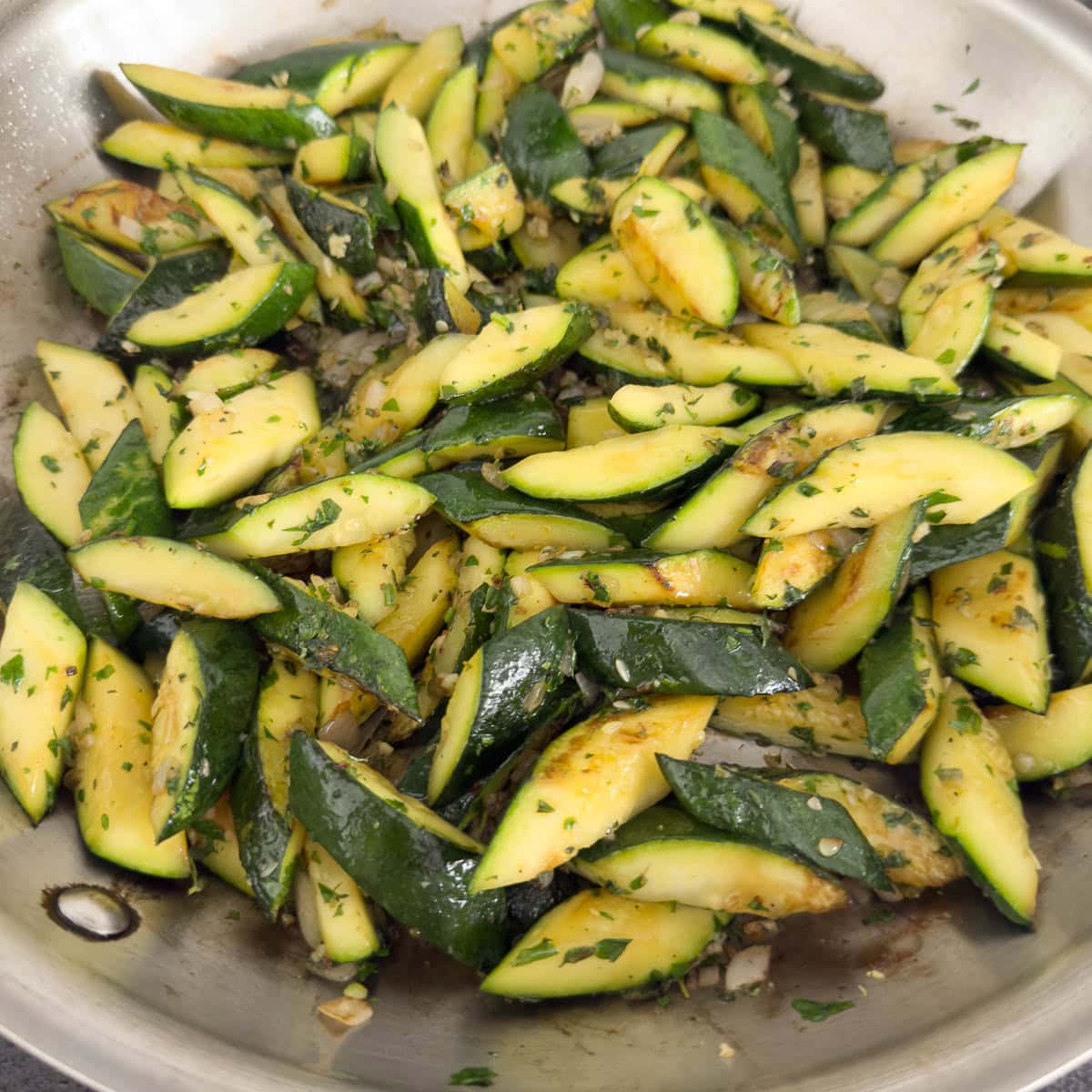 Browned zucchini after sauteing tossed with herbs.