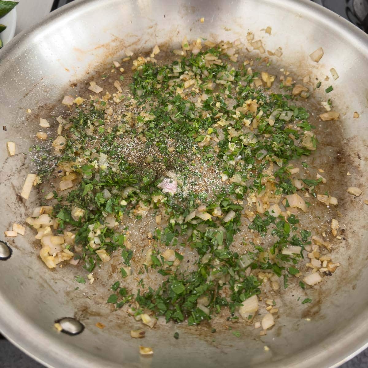 Sautéing shallot, garlic and herbs in a stainless fry pan.