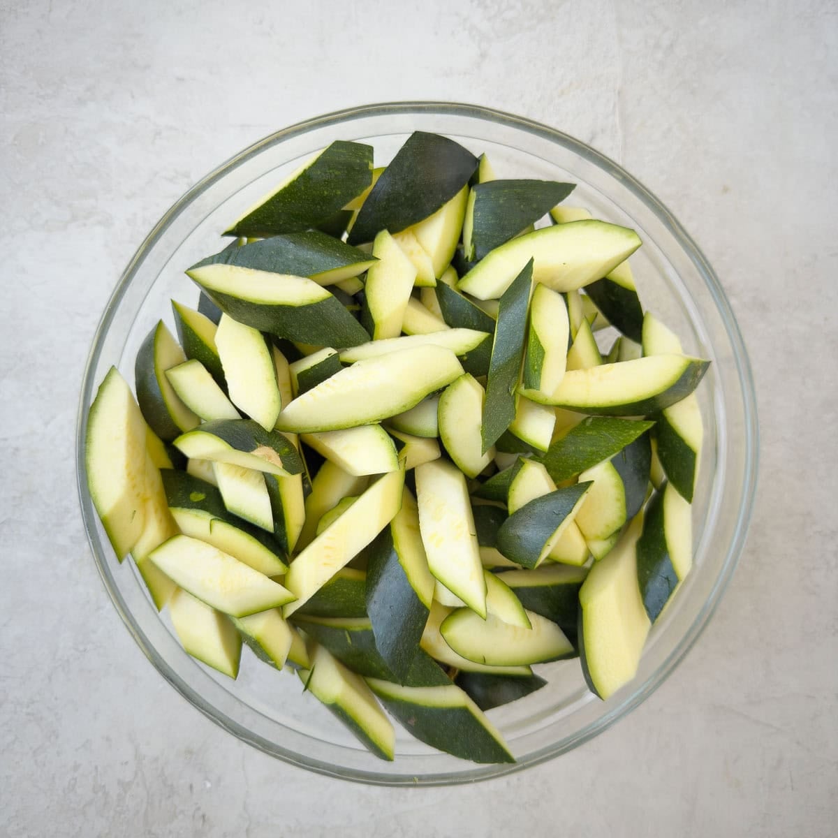 Chopped zucchini in a glass bowl ready for cooking.