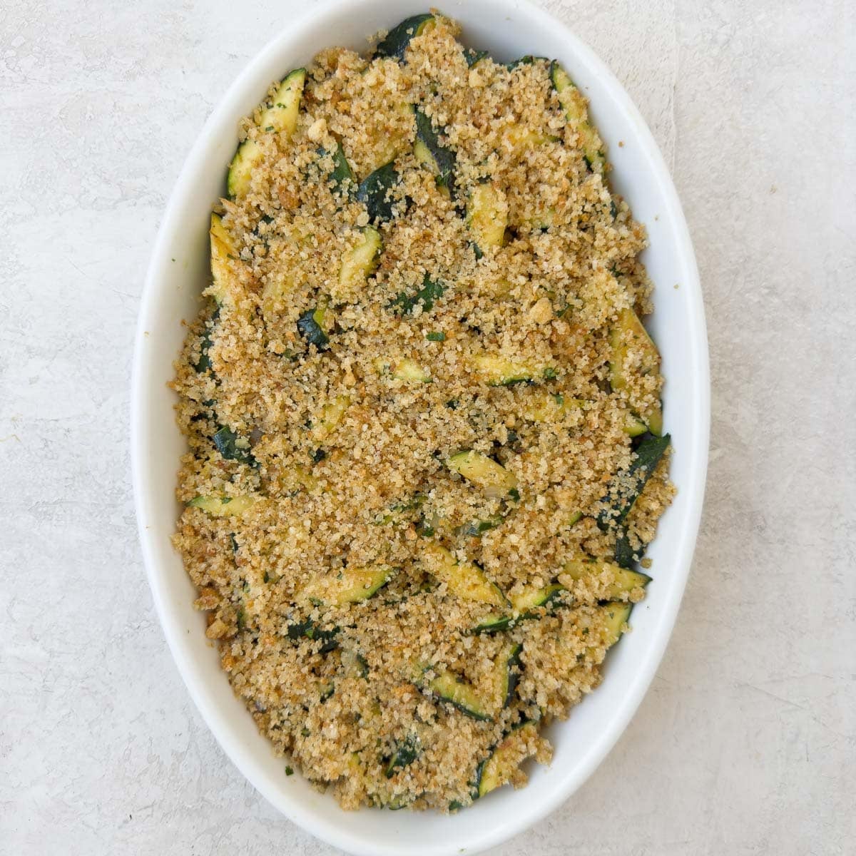 Zucchini casserole with breadcrumb and parmesan topping ready to broil.