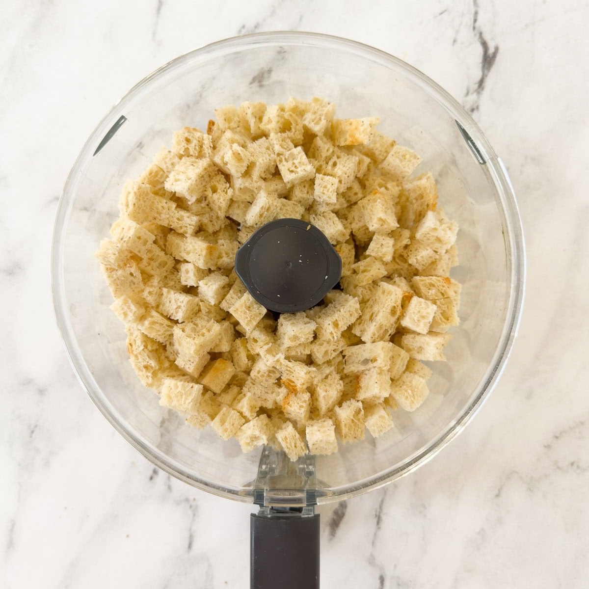 Bread cubes in the workbowl of a food processor.