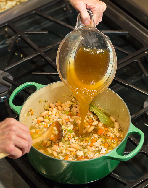 Pouring broth into the pot with vegetables.