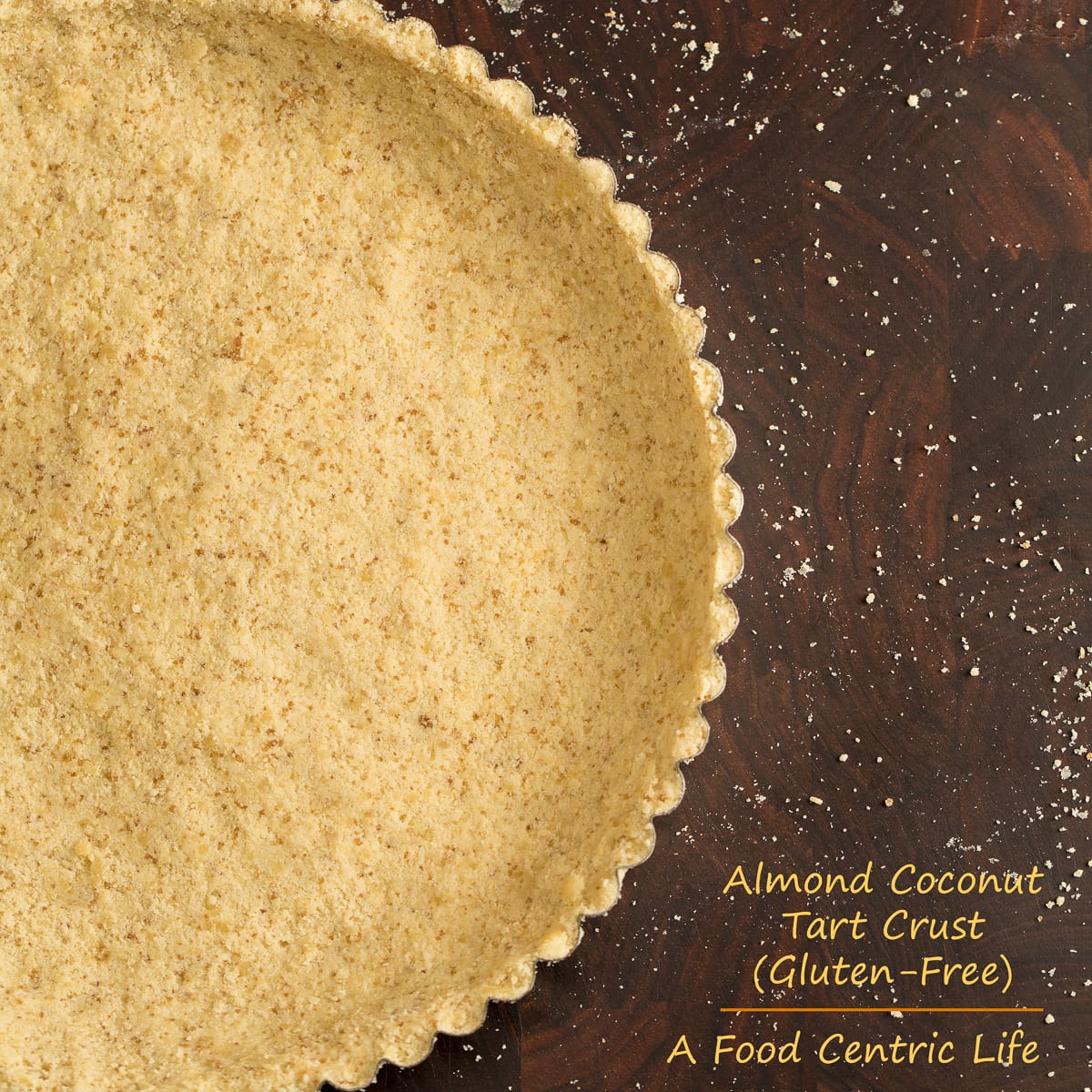 Gluten free almond tart crust ready to fill on a walnut cutting board. 