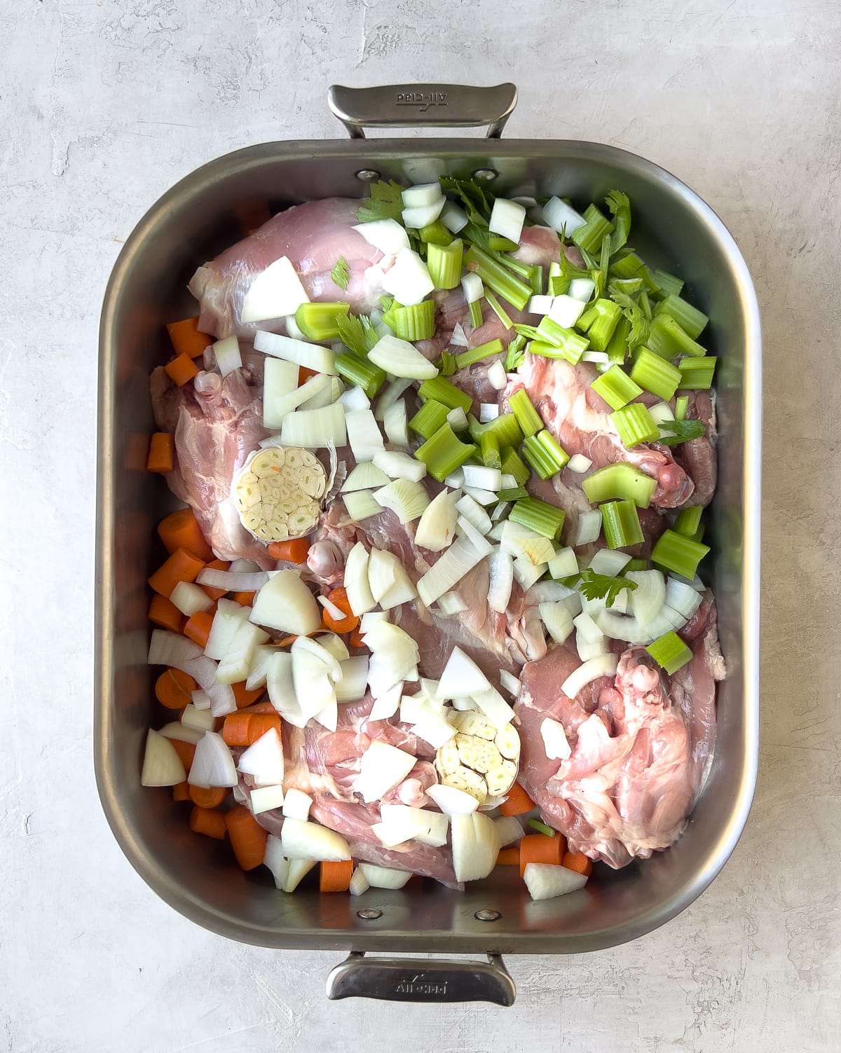 Raw turkey pieces and vegetables in pan.